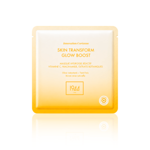 Sheet mask packet labeled Skin Transform Glow Boost in gold tones, with French ingredients and a 1944 Paris logo, on a white-decorated background.