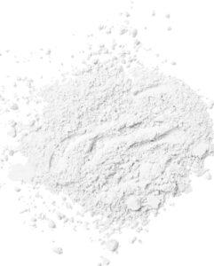 Pile of fine white powder (likely flour) on a white surface with scattered bits nearby.
