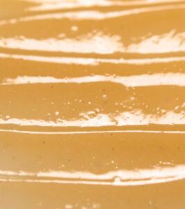 Close-up of a caramel-colored surface with irregular white swirled stripes