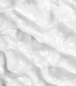 Close-up of white, glossy fabric draped in soft folds and highlights.