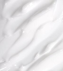 Close-up of glossy white cream or lotion with smooth, flowing swirls.