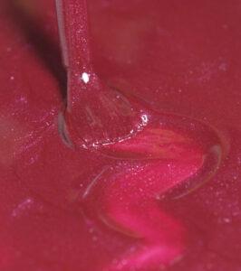Close-up of a dental instrument at the gum line around a tooth in pink oral tissue