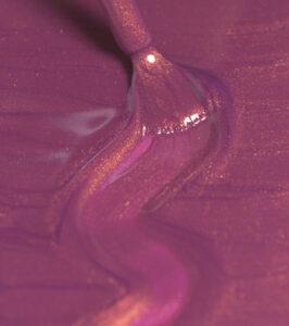 Macro close-up of pink-purple viscous liquid swirling with gold shimmer highlights, creating an abstract glossy pattern