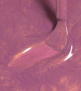 Close-up of purple-pink paint being swirled with a wooden tool, revealing gold metallic specks in the glaze.