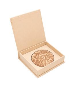 Open beige presentation box containing a round marbled bronzer compact inside the tray.
