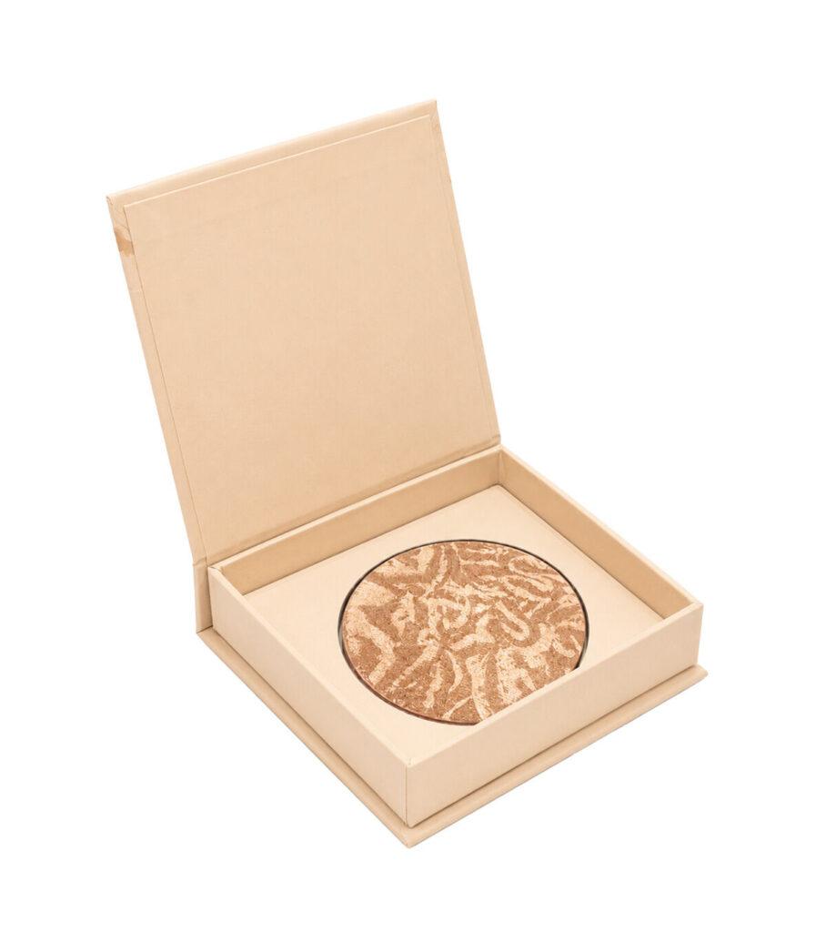 Open beige presentation box containing a round marbled bronzer compact inside the tray.